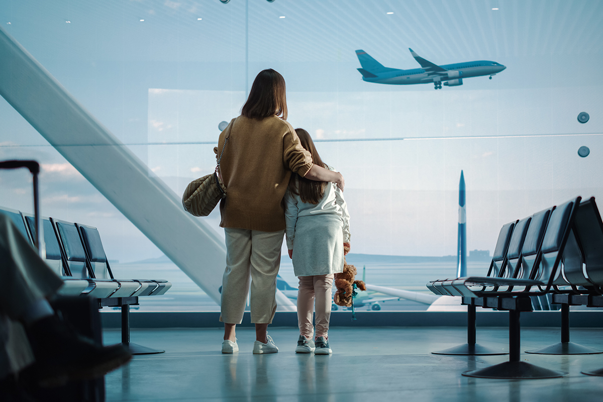 Bilden visar en kvinna och ett barn som ser ett flygplan lyfta.
