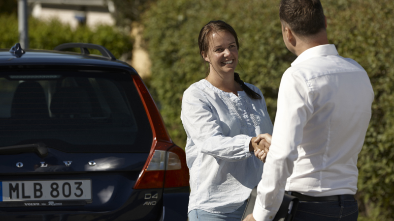 Säljare och köpare skakar hand vid bilköp.