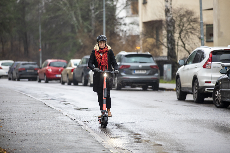 Kvinna som kör elsparkcykel i bostadsområde, fotografi