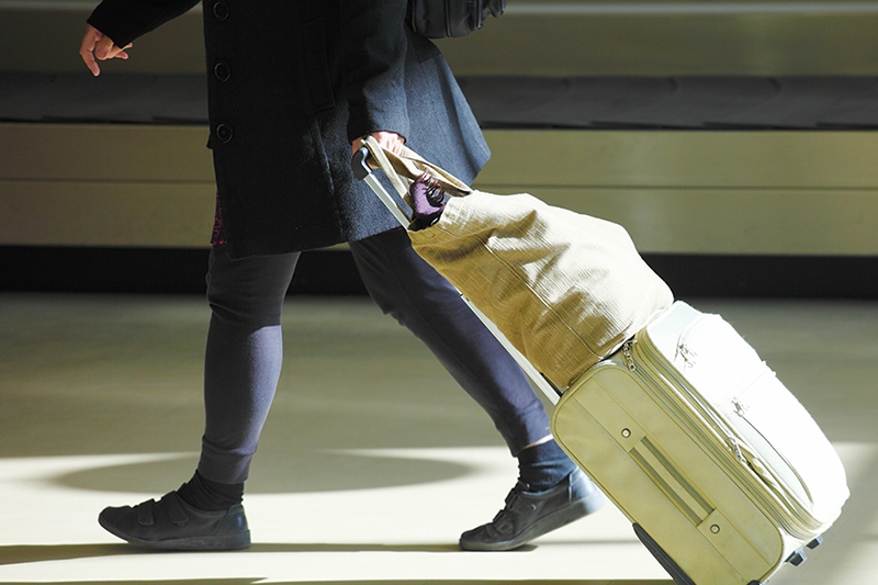 Bilden visar en person som går med en resväska.