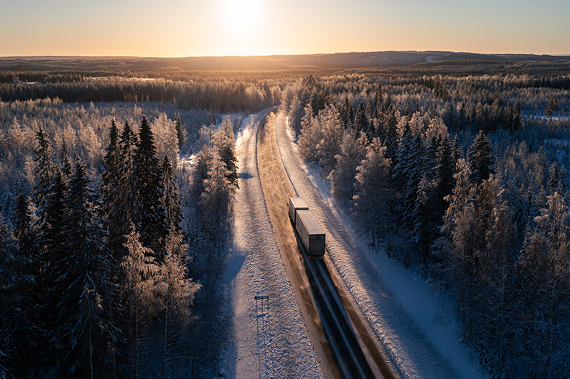 Vinterlandskap med väg och lastbil.